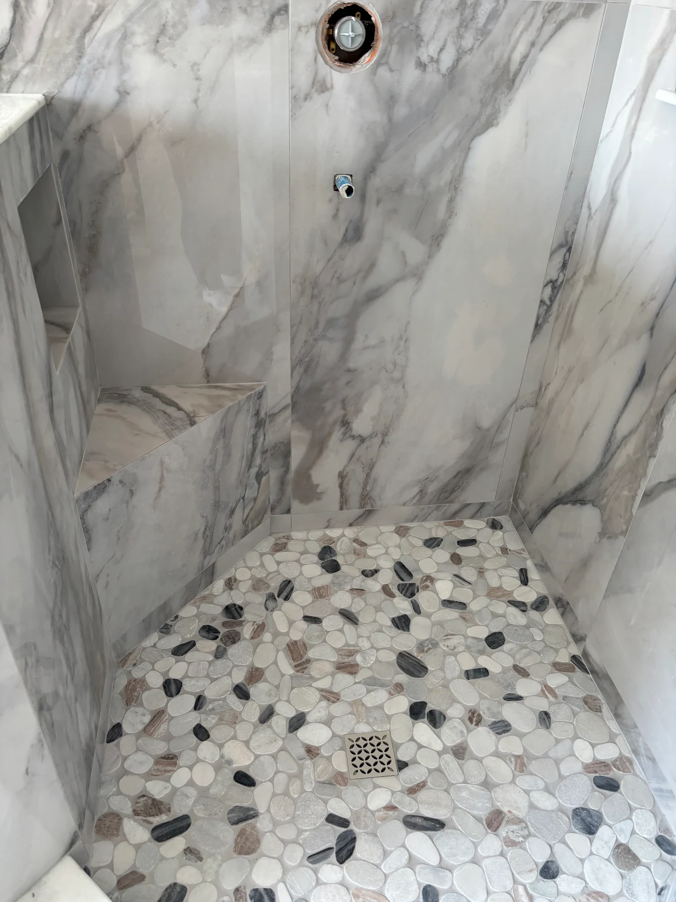 Marble shower with pebble floor and bench